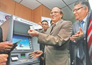 Bangladesh Bank Governor Atiur Rahman shows a banknote at the launch of a national payment switch at the central bank in Dhaka yesterday. The new system will accelerate e-commerce in Bangladesh. Photo: STAR